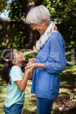 Side view of grandmother and daughter standing while holding hands