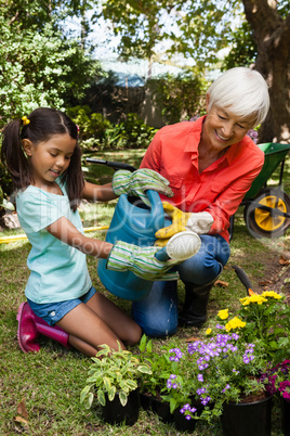 Smiling granddaughter and grandmother watering plants