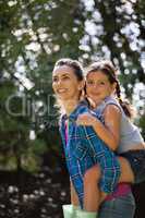 Smiling mother piggybacking daughter