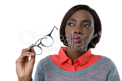 Woman looking away while holding eyeglasses