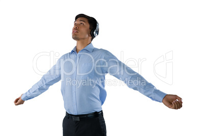 Businessman listening music while standing with arms outstretched