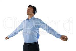 Businessman listening music while standing with arms outstretched