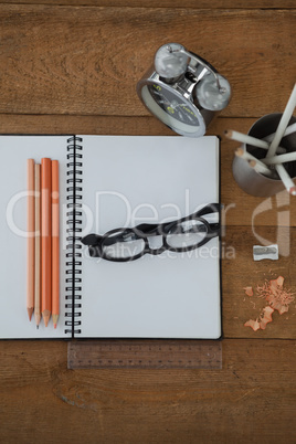 Alarm clock, book, pencil, scale, spectacles and sharpener on wooden table