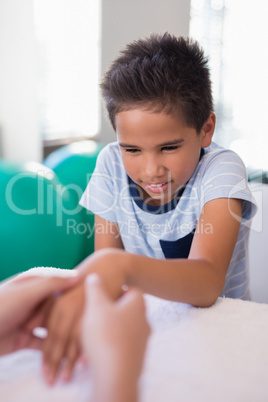 Cropped hands of female therapist massaging hand while boy sitting at table