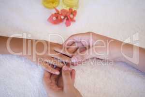 Female therapist examining hand of boy on white towel