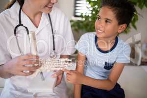 Smiling boy touching artificial bone held by female therapist