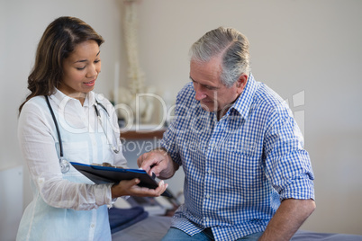Senior male patient pointing at file while discussing with female therapist