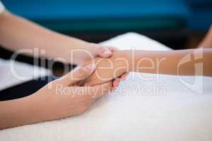 Close-up of female therapist holding hands while examining on white towel