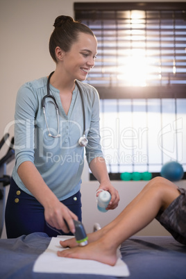 Happy female therapist looking away while scanning feet of boy