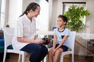 Smiling boy and female therapist sitting with digital tablet