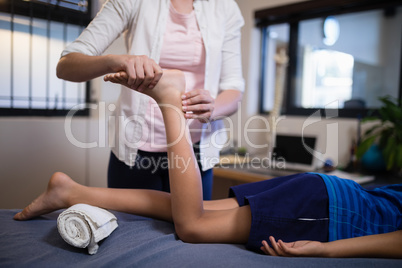 Low section of boy receiving foot massage from young female therapist