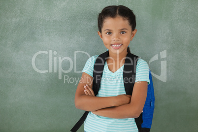 Portrait of cute school girl standing with arms crossed
