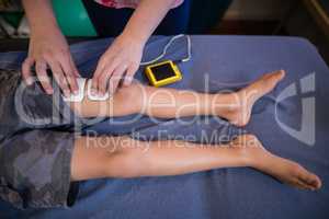 High angle view of female therapist placing electrodes on leg