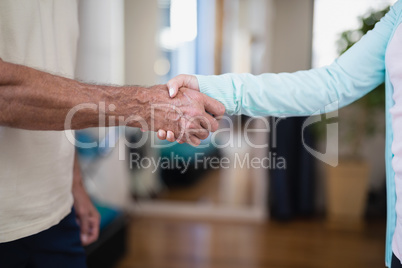 Midsection of senior male patient shaking hands with female therapist