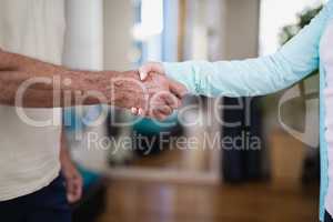 Midsection of senior male patient shaking hands with female therapist