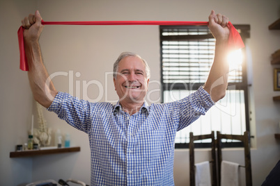 Portrait of smiling senior male patient holding red resistance band