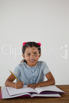 Young girl writing in her book against white background