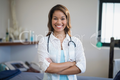 Portrait of smiling young female therapist standing with arms crossed