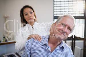 Portrait of female therapist giving neck massage to senior male patient