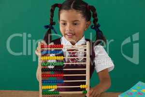 Schoolgirl using abacus against chalkboard