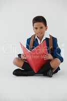 Schoolboy reading book on white background