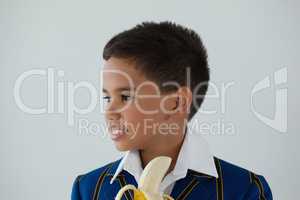 Schoolboy having banana against white background