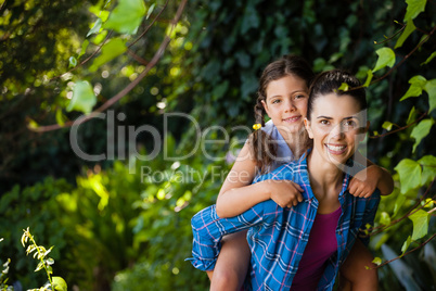 Portrait of cheerful woman piggybacking daughter