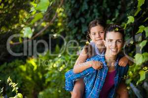 Portrait of cheerful woman piggybacking daughter