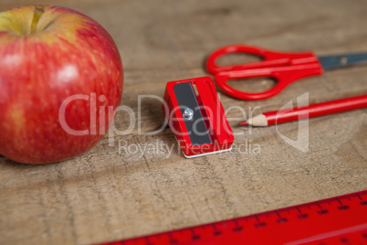 Apple and school supplies on wooden table