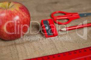 Apple and school supplies on wooden table