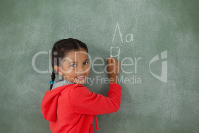 Young girl writing on chalk board