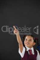 Schoolgirl pointing against blackboard in classroom