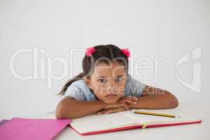 Young girl with her head on desk against white background
