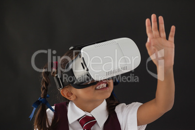 Schoolgirl using virtual reality headset against blackboard