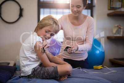 Female therapist positioning electrodes on arm of boy