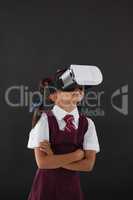Schoolgirl using virtual reality headset against blackboard