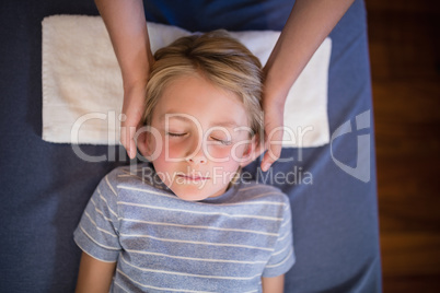 Overhead view of boy with eyes closed receiving neck massage from female therapist