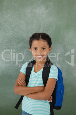 Portrait of cute school girl standing with arms crossed