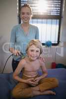 Portrait of smiling female therapist holding ultrasound machine with shirtless boy