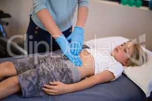 High angle view of female therapist examining stomach
