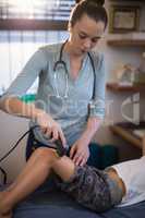 Young female therapist using ultrasound machine on knee of boy