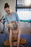 Female therapist scanning shoulder of shirtless boy with ultrasound machine