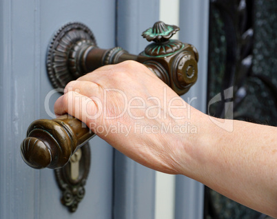 Female hand with old handle bar opening door