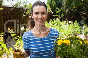 Portrait of smiling beautiful woman holding trowel and flowering pot