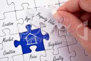 Property Value - female hand with real estate puzzle