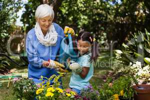Smiling grandmother and granddaughter watering plants