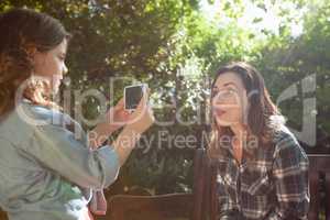 Side view of girl photographing mother sticking out tongue