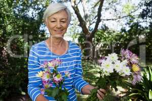 Smiling senior woman looking at fresh flowers