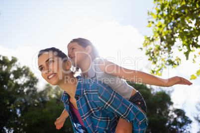 Girl with arms outstretched enjoying piggyback ride on mother