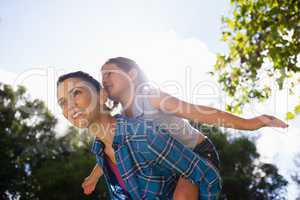 Girl with arms outstretched enjoying piggyback ride on mother